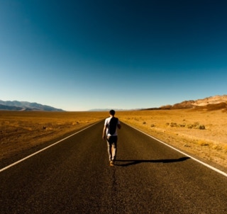 Man with backpack walking down a road
